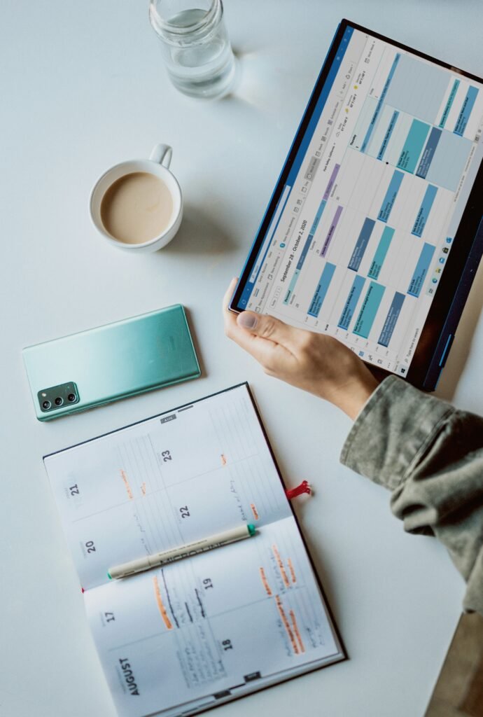 table with planner and person holding a tablet displaying a digital calendar, software for creatives, best project management platforms, small business productivity
